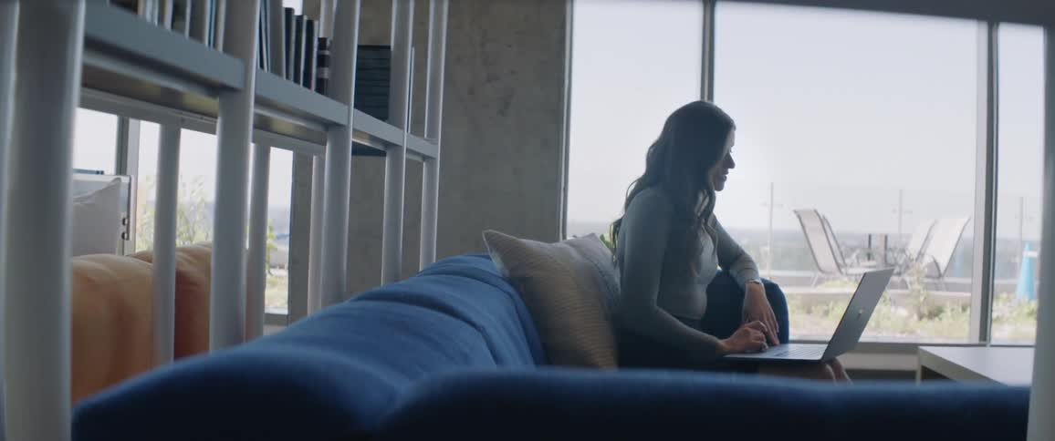 Woman sitting on a blue sofa using a laptop