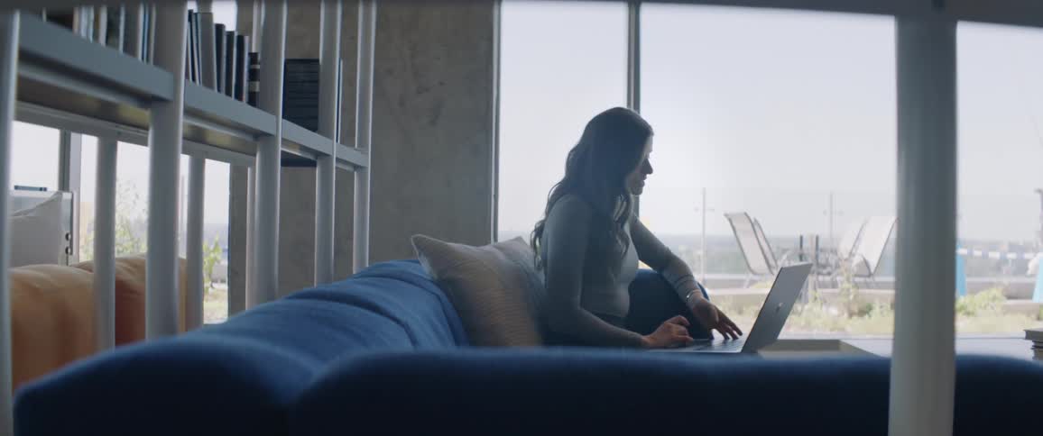 Woman sitting on a sofa typing and working on a laptop