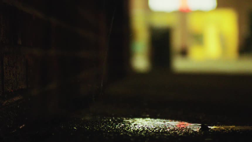 Closeup of a wet floor next to a brick wall with falling water