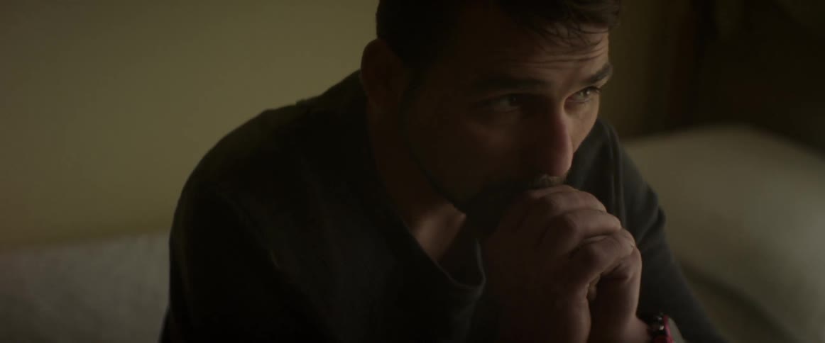 A man sits with his chin on his hands