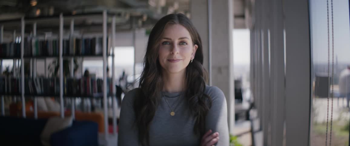 Woman in a work environment crossing her arms and giving a slight smile