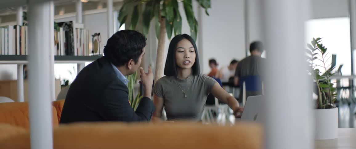 A man and a woman are sitting on a sofa and the woman is talking to him