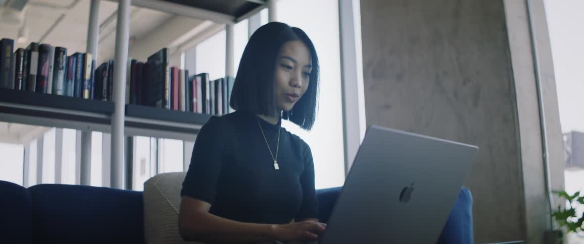 A woman is talking and typing on her laptop