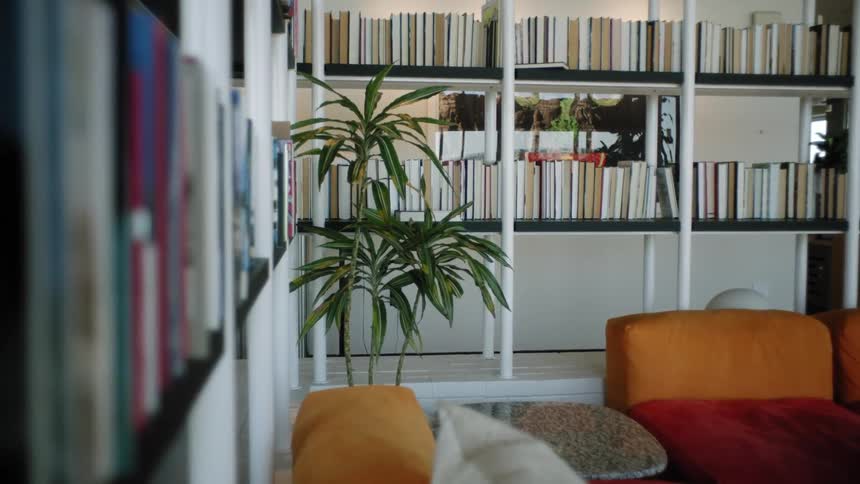 Interior architecture of a room with orange armchairs and cabinets with stacks of books