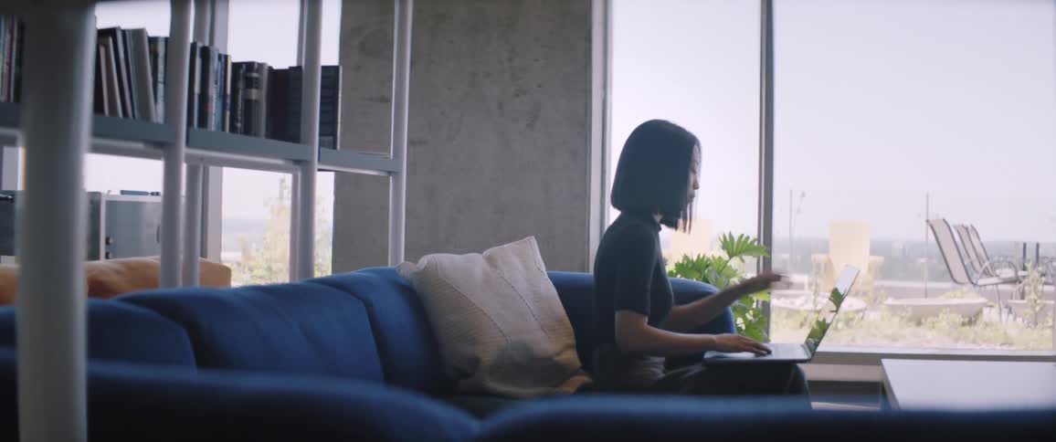 A woman is typing on a laptop in the office lobby