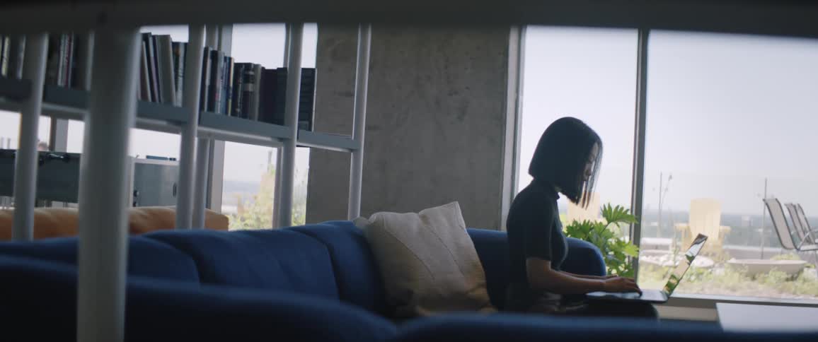 A woman is on the couch typing on her laptop