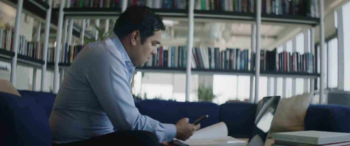 Man in a work environment photographing a book with his cell phone