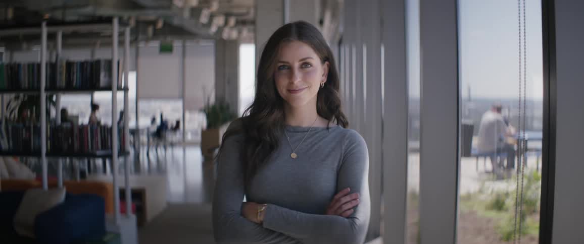 Woman in a room with bookshelves crossing her arms and smiling