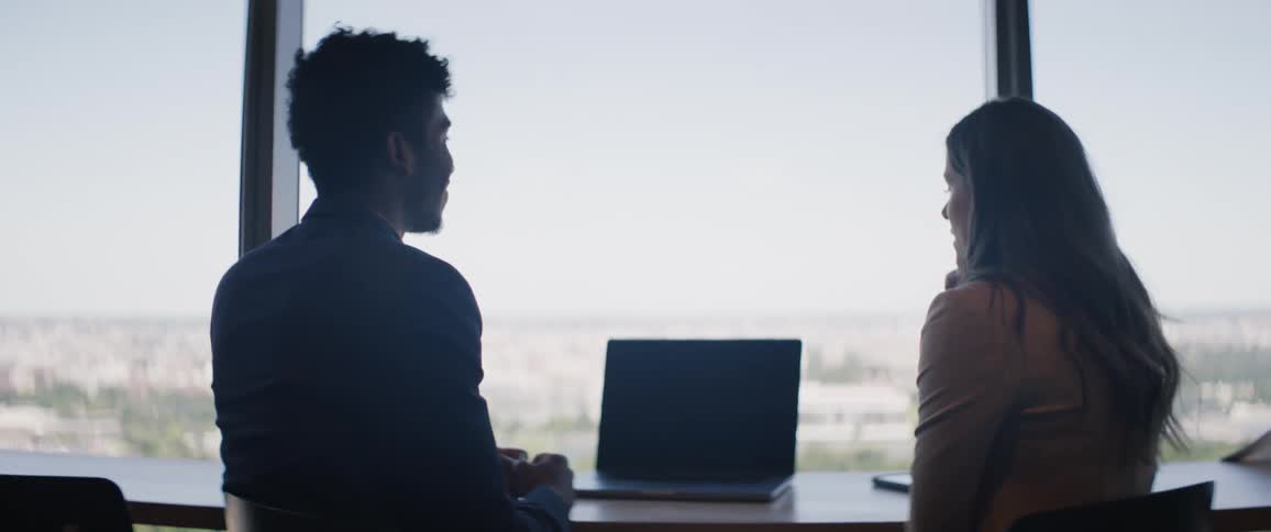 A woman and man have a discussion centered around a laptop