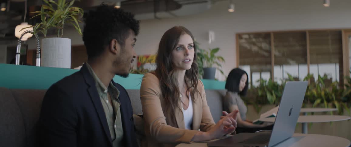 Coworkers are talking in the office by a laptop