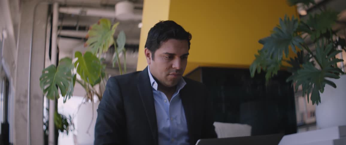 Man sitting in an armchair concentrated typing on his laptop