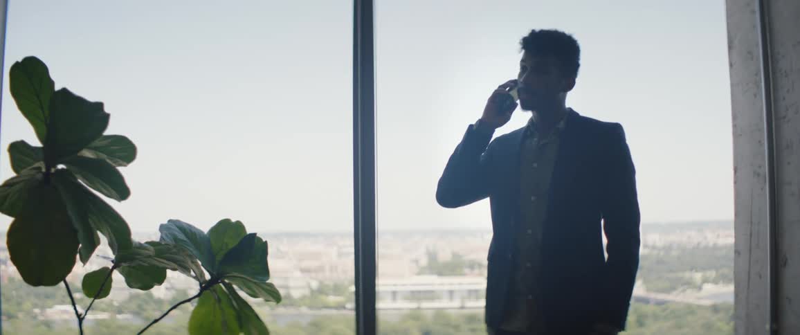 Man in blazer indoors answering a phone call
