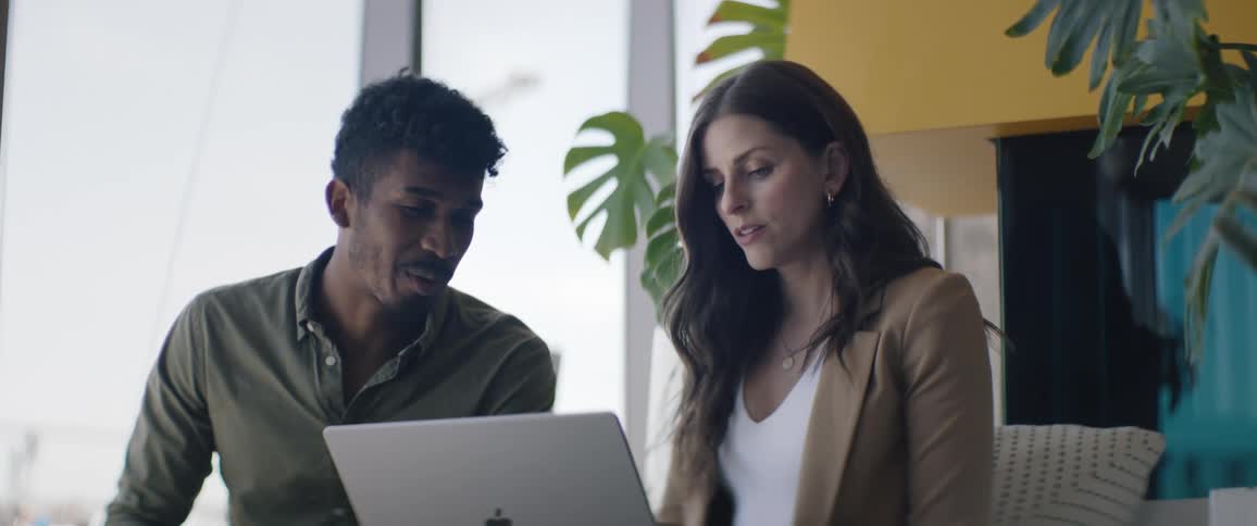 Man and woman sitting talking and using a laptop