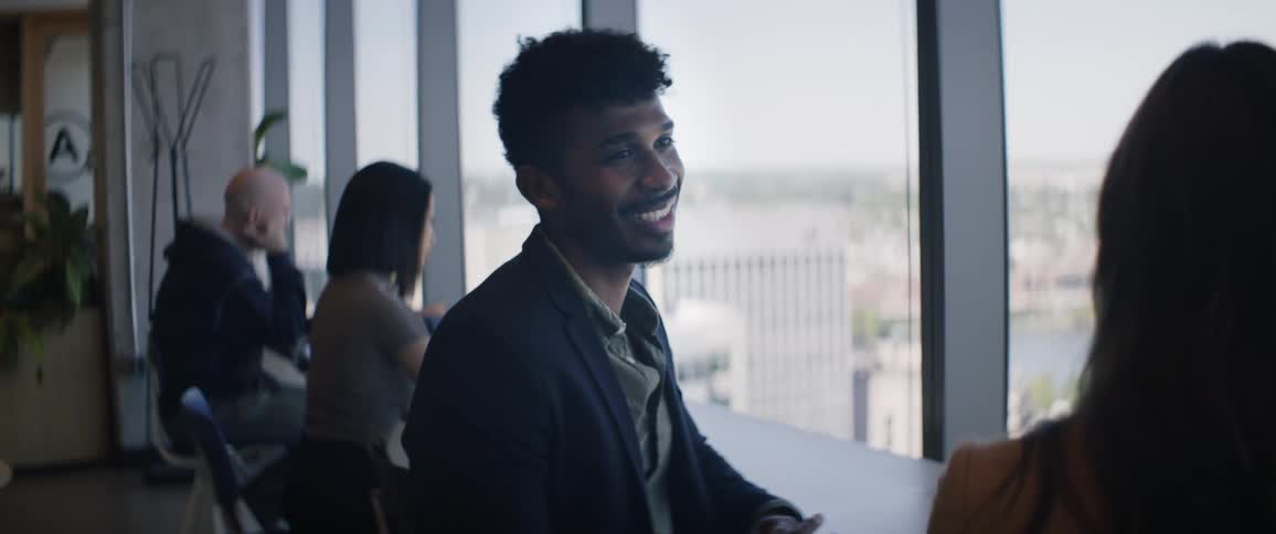 Smiling man talking to a woman next to him indoors in a building