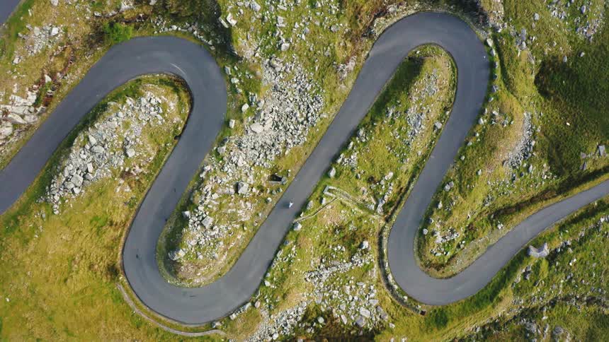 Overhead top down shot of curvy chicane road with cyclist