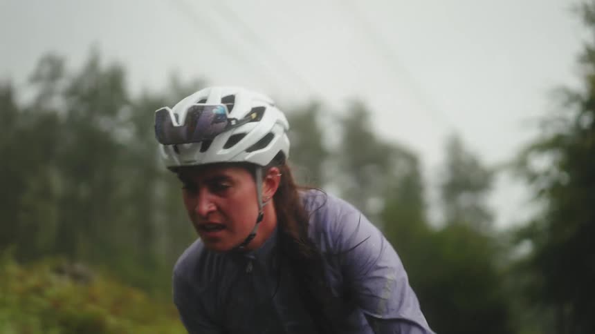 A woman rides a bike on a path through the woods determined