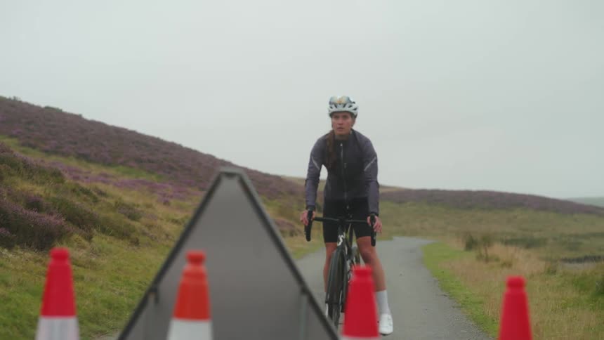 Cyclist woman riding her bike on a narrow street and stopping when she arrives at a road block