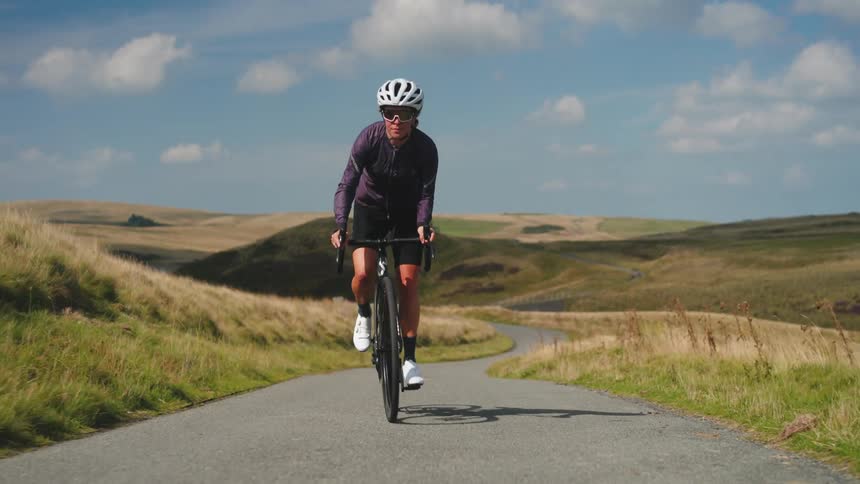 Cyclist woman riding her bike up a hill in nature
