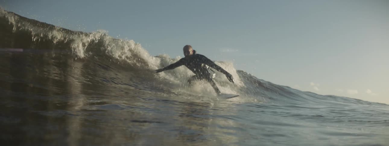 A surfer rides a wave during the day