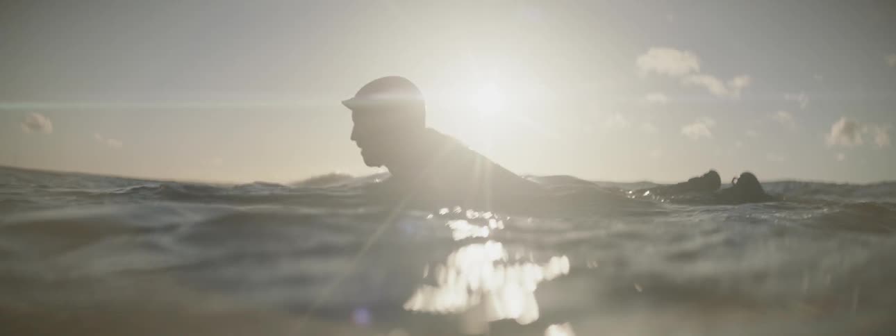 Surfer floating and paddling in ocean water