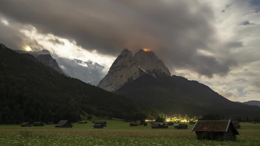 Rural area with small wooden houses and surrounding mountain ranges and the day getting dark