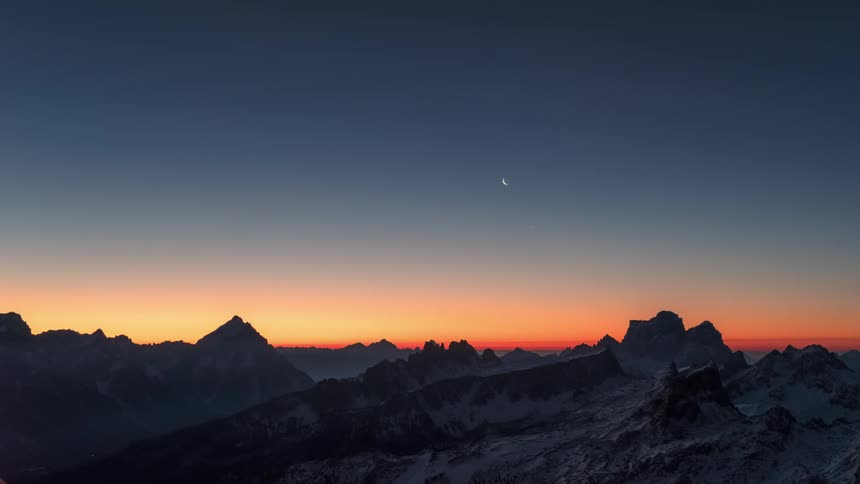 Night landscape of snowcovered mountains under a starry sky and the dawning day