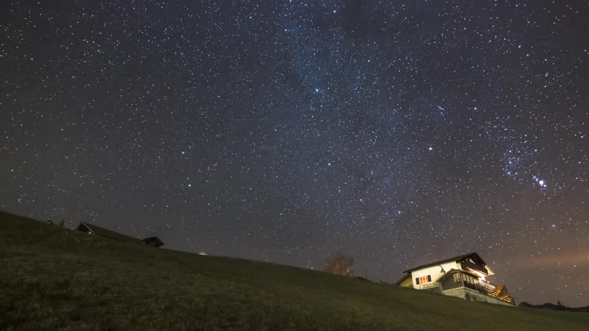 A serene night sky filled with stars above a gently sloped landscape