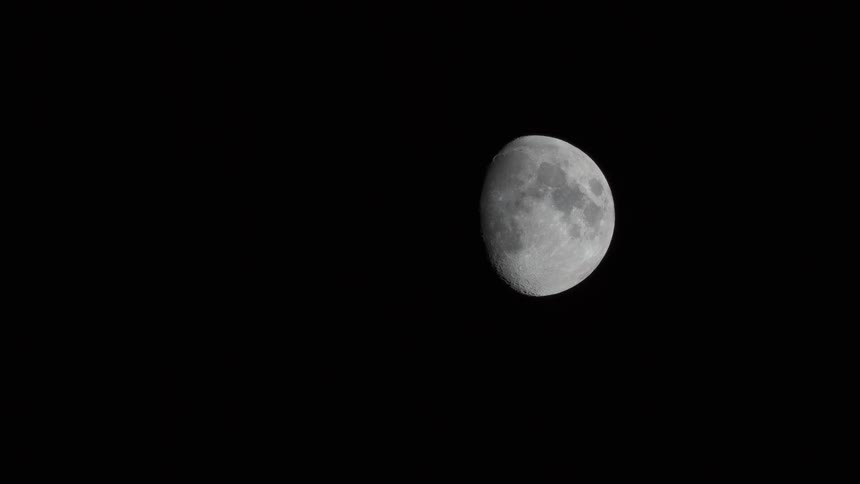 A three quarter moon passes in the night sky