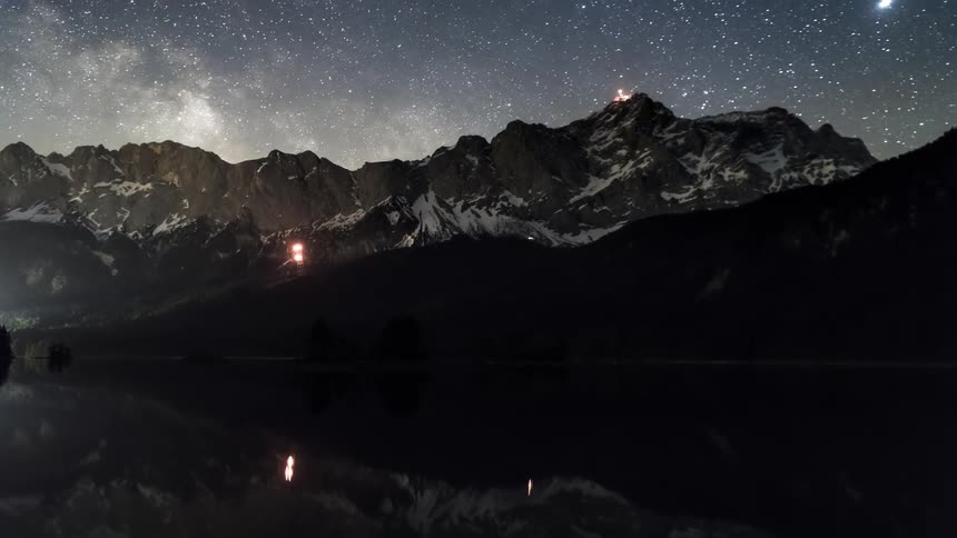 A star filled night sky with the milky way galaxy spanning above silhouetted mountain peaks