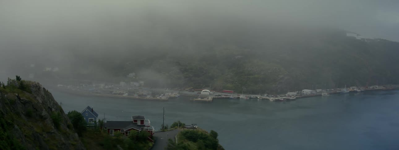 Scenery of a shipping canal with mountains around and houses by the sea