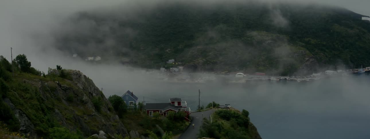 A serene village by the water shrouded in mist in the mountains