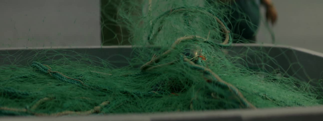 Tangle of green wires and ropes on a metallic surface and a person in the background pulling