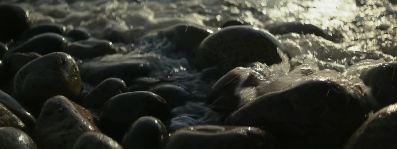 Several smooth rocks on the sea coast with a small wave hitting them