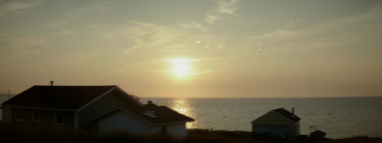 Small houses by the sea with sunrise on the horizon