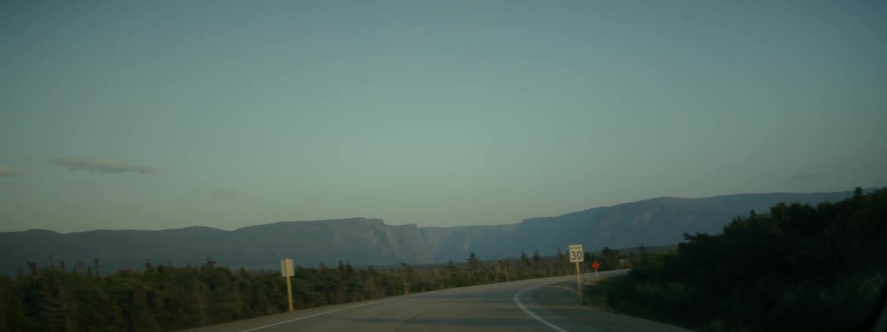 A twolane empty road in the mountains under a clear sky