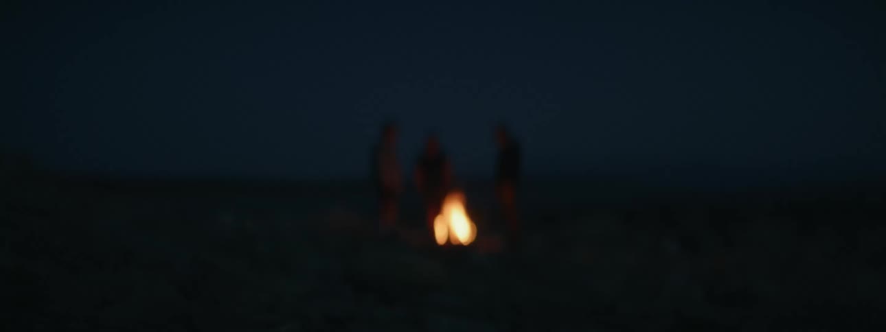 Blurry footage of a distant campfire burning in the night