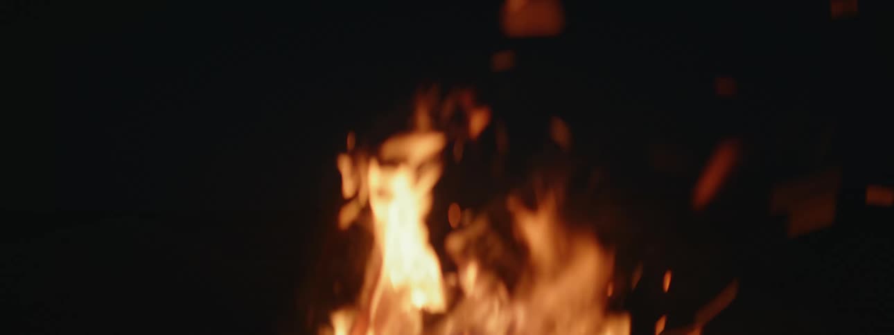 Sparks fill the air from roaring campfire at night