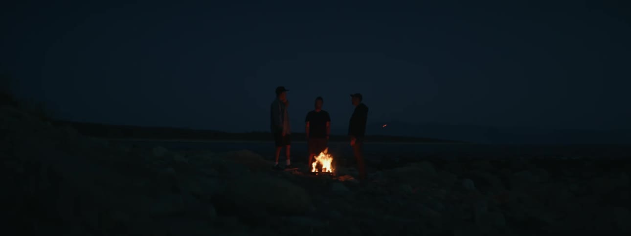 Natural scenery with silhouette of three people around a small fire at night