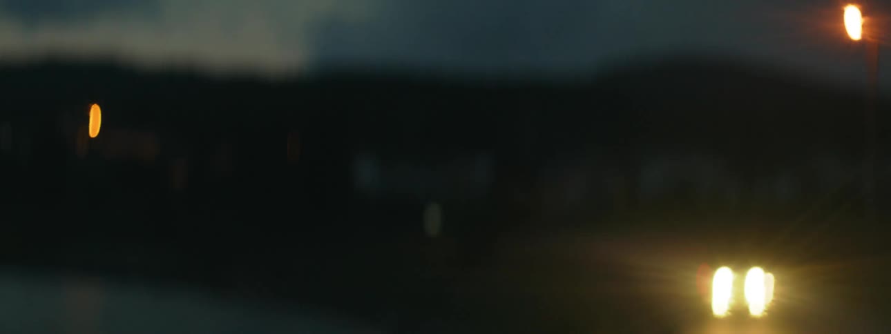 Blurry footage of bright headlights of a vehicle driving at night