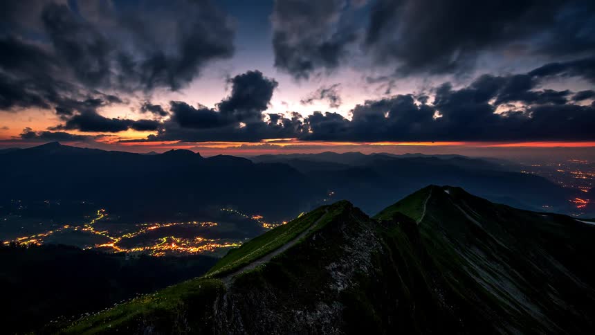 Mountain towers over town with lights that glow brightly as night falls