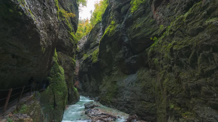 Creek in the middle of mountainous rock walls with tourists passing by