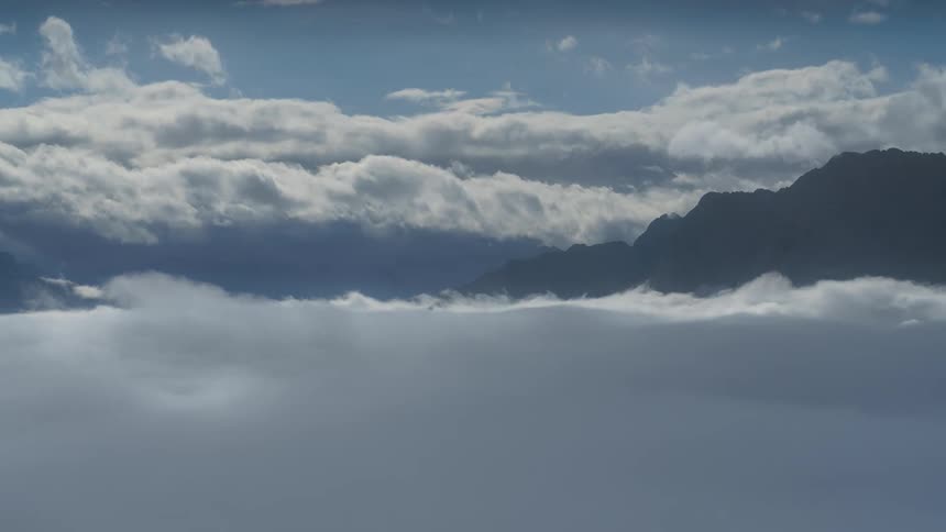 Landscape of dense dark clouds in the sky with the silhouette of mountains in the background