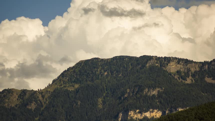 Thick clouds flow over forested mountains on a misty day