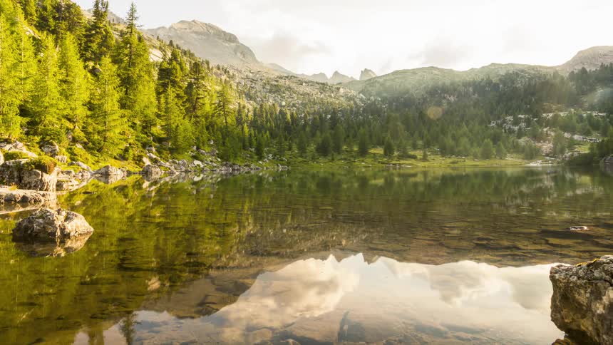 Clouds flow over the mountains and reflect on the lake