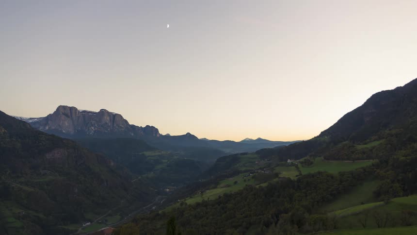 A valley between mountains with a busy street at dusk