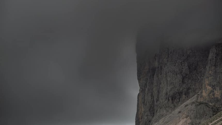 Dark storm type clouds swirl around a mountain cliff