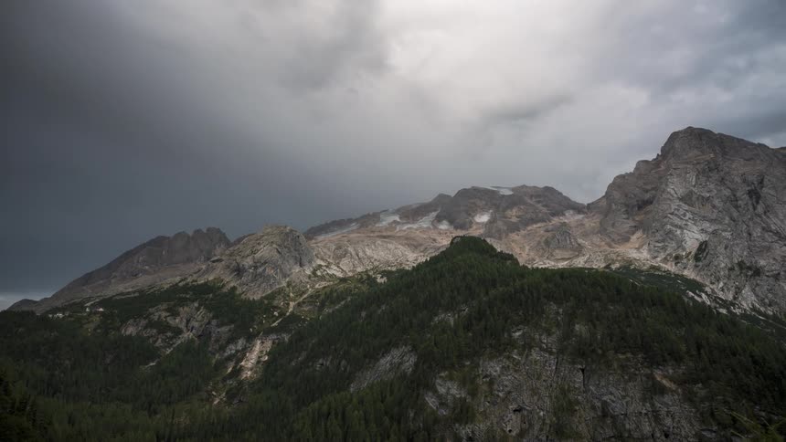 Time lapse of a towering mountain range under a dark stormy sky