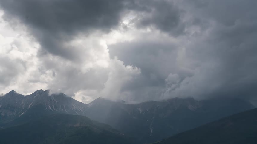 Mountain landscape with jagged peaks under a dramatic cloudy sky