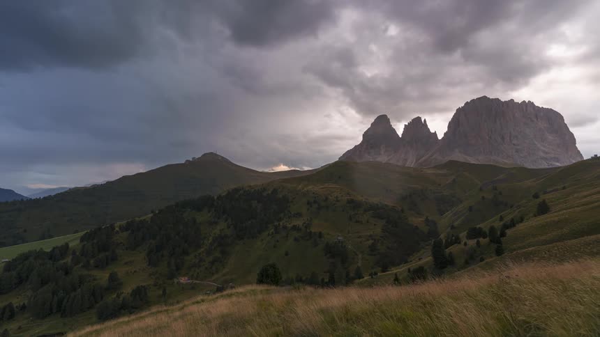 Time lapse of clouds rolling over a landscape with steep mountain peaks
