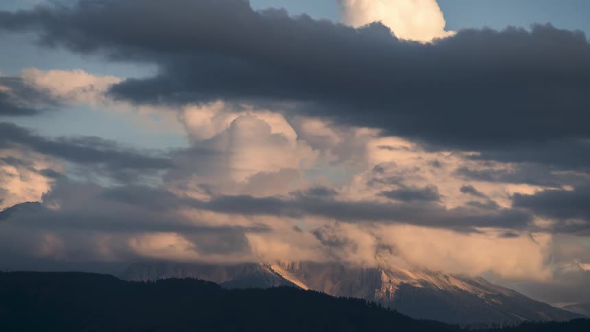 Large clouds sit on the peak of the mountain